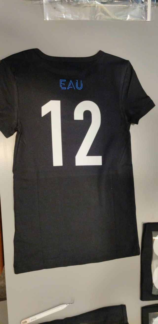 Dos d'un t-shirt noir pour enfant avec le numéro 12 en vinyle blanc et le mot « EAU » en bleu.