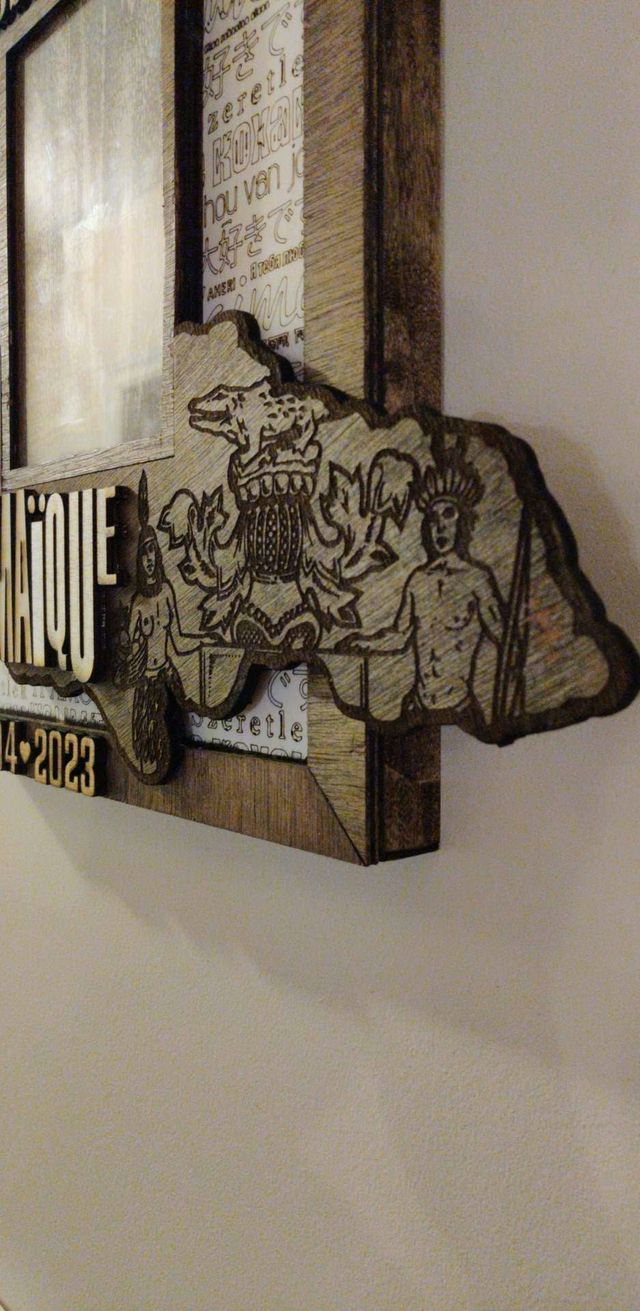 Gros plan de la carte de la Jamaïque découpée dans le bois et gravée des armoiries du pays, posée en relief sur le cadre souvenir.