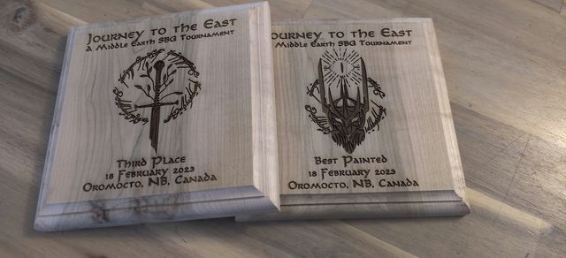 Deux plaques trophées en bois gravées pour le tournoi « Journey to the East » sur le thème de la Terre du Milieu : troisième place et meilleure peinture, février 2023.